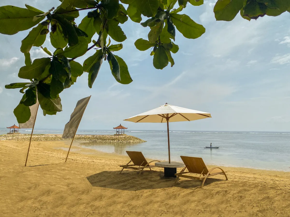 Sun loungers and a parasol on the quiet sand at éL Hotel & Resort, Sanur