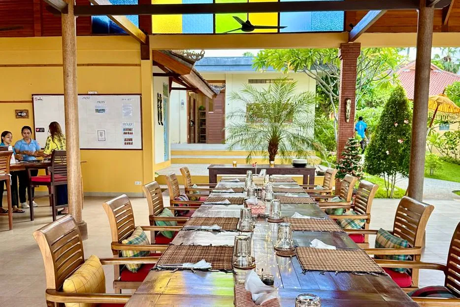 A long communal table set for dinner under the pavilion's stained-glass roof