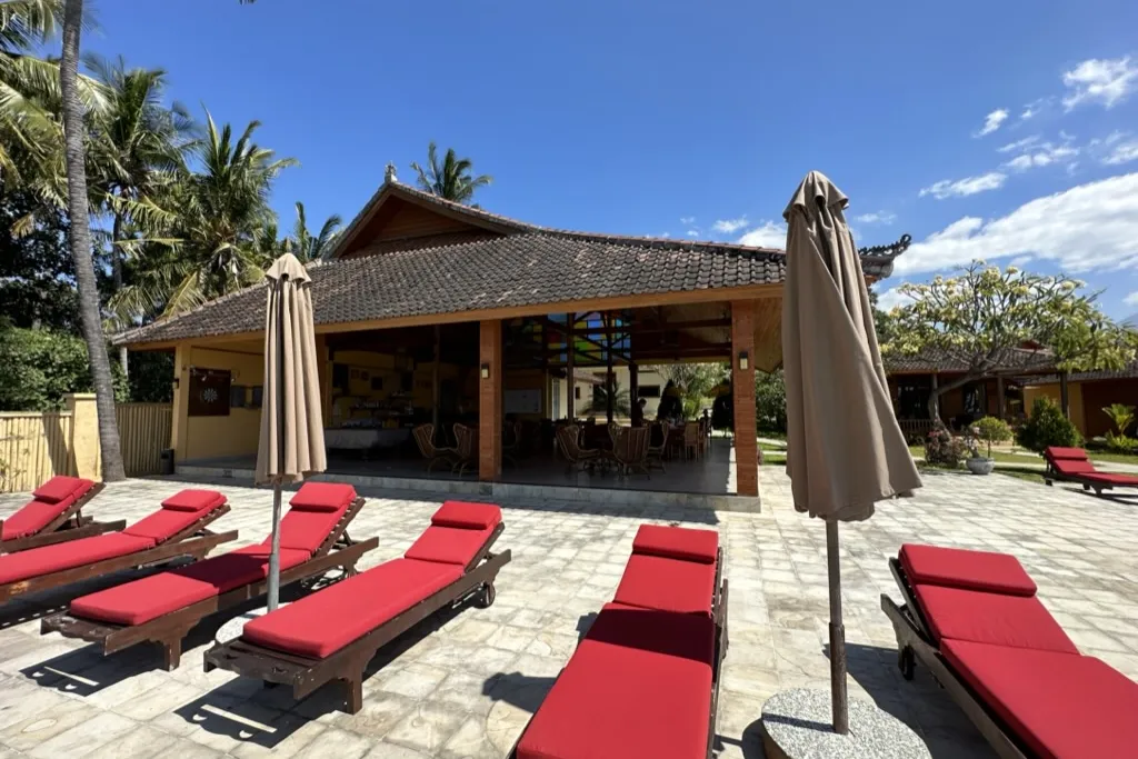 The open-air Balinese pavilion at ABWonderdive with red sun loungers on a tiled terrace