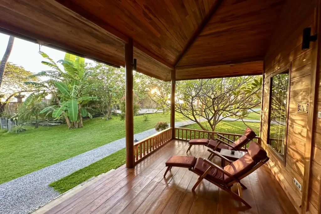 A teak bungalow veranda opening onto the resort's tropical garden at golden hour